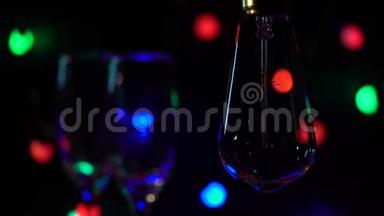 两杯香槟被点燃在灯泡的背景下，闪亮的手电筒背景。 关门